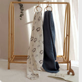 Penguin swaddle and navy blanket hanging together from a crib rail